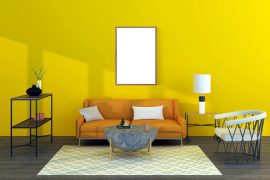 Salon décoré et composé d'un canapé, d'un fauteuil et d'une table basse avec un mur jaune au fond